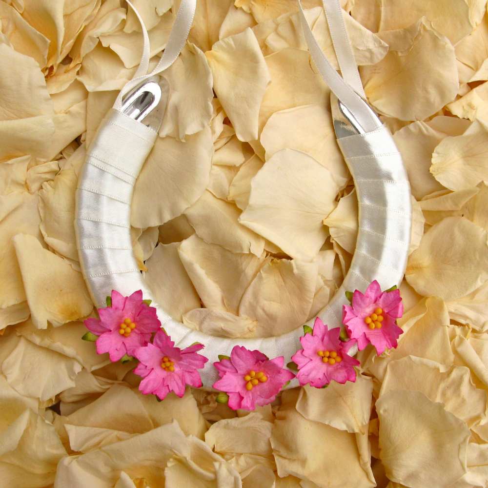 A lucky wedding horseshoe for the bride decorated with pink paper flowers.