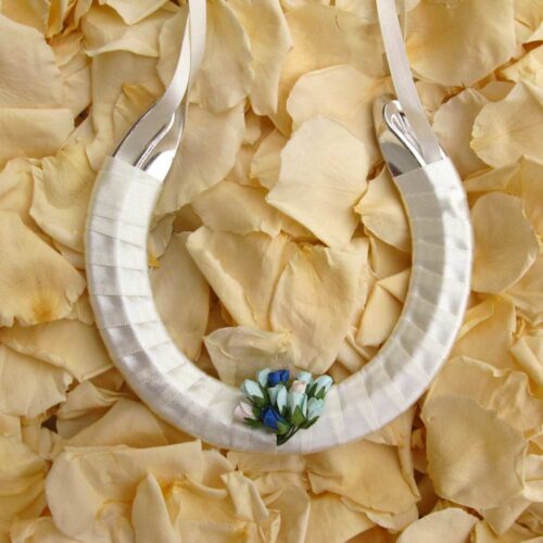 A lucky wedding horseshoe for the bride decorated with blue paper rose buds.