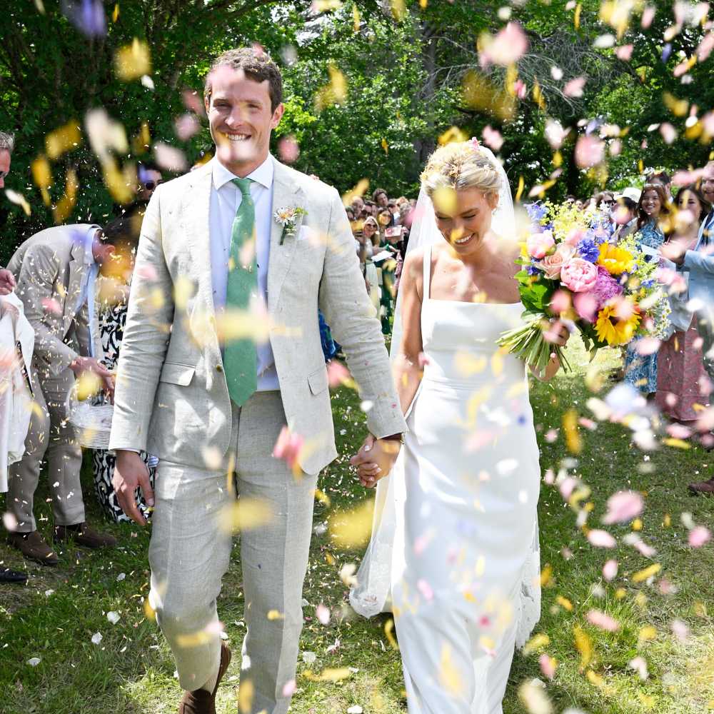 A bride and groom holding hands and enjoying their colourful confetti moment